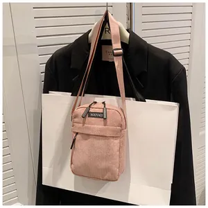 Detailed texture of pink corduroy shoulder bag with adjustable strap and front pocket