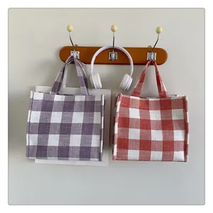 Détail de sacs fourre-tout à carreaux violets et orange suspendus à un crochet en bois pur