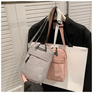 Detail view of corduroy shoulder bags in grey and pink with adjustable woven straps
