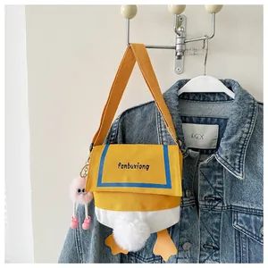 Detail view of cute cartoon duck canvas crossbody bag with plush charms and vibrant colors