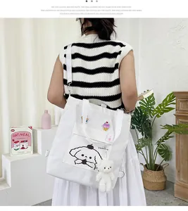 Détail du sac en toile blanche avec motif de chien cartoon et peluche d'ours