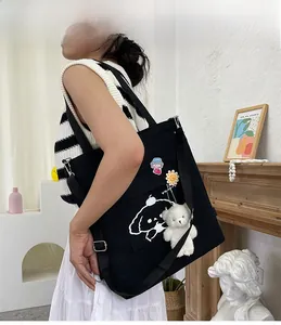 Détail du sac fourre-tout en toile noire avec imprimé cartoon et breloque ours en peluche
