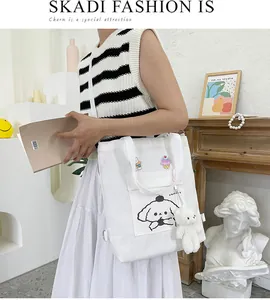 Détail du sac cabas en toile blanche avec broderies cartoon et porte-clé ours peluche