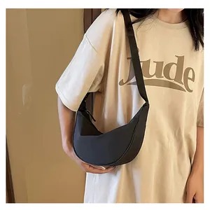 Dettaglio della grande borsa a mezzaluna nera indossata a spalla da una modella con stile