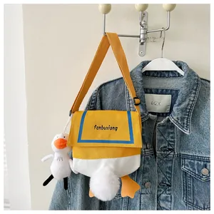 Close-up of cute cartoon duck canvas crossbody bag with yellow feet and plush charms