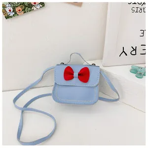 Nahaufnahme einer blauen Kinderhandtasche mit roter Schleife auf einem Podest