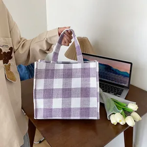 Grand sac à main cabas à carreaux violets et blancs posé sur un bureau en bois