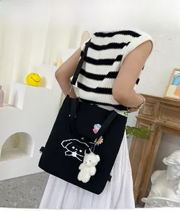 Détail du sac cabas en toile noire avec imprimé cartoon et breloque ours en peluche