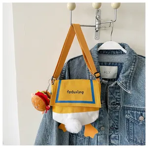 Detail of cute cartoon duck canvas crossbody bag with fluffy tail and hamburger charm
