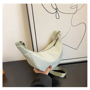 Dettaglio della borsa a mezzaluna in nylon verde chiaro con texture liscia e tracolla