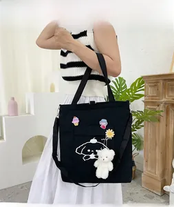 Détail du sac en toile noire avec motif chien, écussons mignons et pendentif ours en peluche