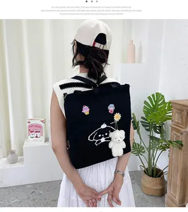 Détail d'un sac à dos en toile noire avec broderie mignonne et pendentif ours