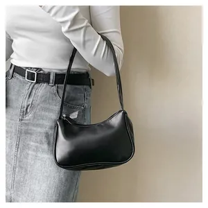Detailansicht einer schwarzen, glänzenden Hobo-Umhängetasche aus Kunstleder mit Sichel-Design