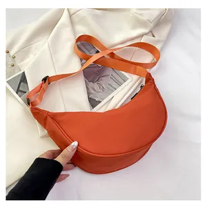 Dettaglio della borsa a mezzaluna in nylon arancione con ampia tracolla in tessuto regolabile