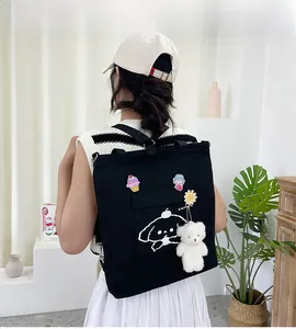 Détail du sac fourre-tout en toile noire avec imprimé chien et breloques en peluche