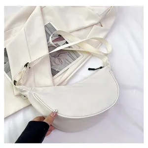 Dettaglio di una borsa a tracolla a mezzaluna bianco crema minimalista in nylon liscio