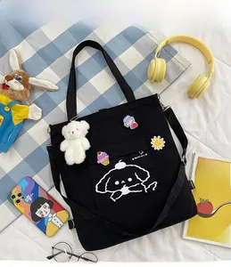 Détail d'un sac fourre-tout en toile noire avec imprimé chien et breloque ours en peluche