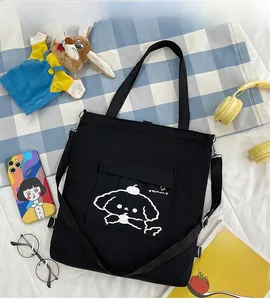 Détail du sac fourre-tout noir en toile avec imprimé chien et poche frontale pratique