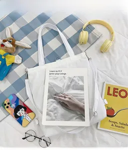 Détail d'un sac cabas en toile blanche avec bandoulière réglable et poche frontale