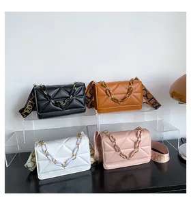 Close-up of quilted crossbody bags with chunky chain and wide printed shoulder straps