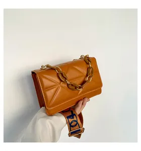 Detailed view of caramel leather crossbody bag with acrylic chain and wide patterned strap