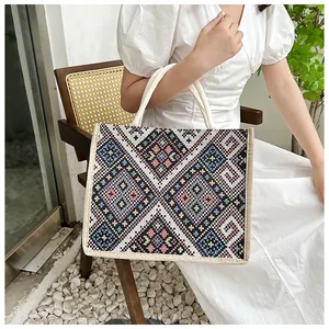 Borsa tote in tela stile etnico con motivi geometrici e manici intrecciati su modella