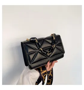 Detail of black quilted shoulder bag with acrylic chain handle and patterned wide strap
