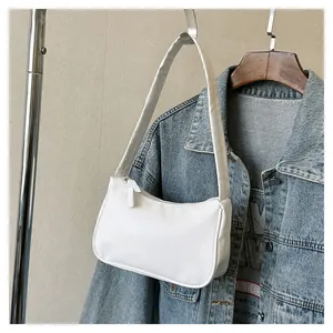 Detailansicht der weißen PU-Leder Baguette Tasche am Kleiderbügel mit Denim Hintergrund