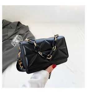 Detail of black quilted crossbody bag with textured pattern and gold chain handle