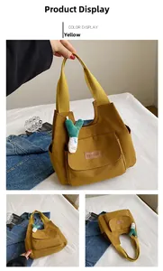 Detail view of mustard yellow canvas tote bag with side pocket and plush scalloped pendant
