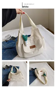 Detail of white canvas tote bag with brown fashion patch and green plush charm