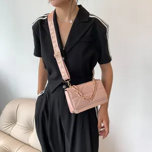 Pink quilted crossbody bag with chic acrylic chain handle and wide patterned strap