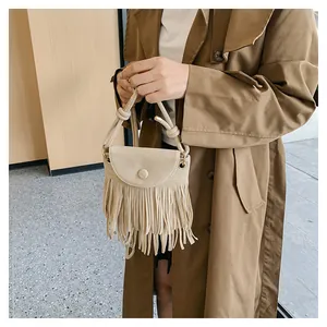 Détail d'un sac à bandoulière beige à franges avec boucle ronde et glands sur modèle