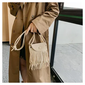 Détail du sac bandoulière crème avec de longues franges et un fermoir rond élégant