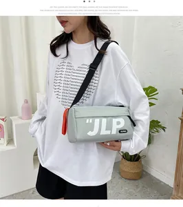 Macro detail of a light green cylindrical crossbody bag with JLP logo and red zipper pull