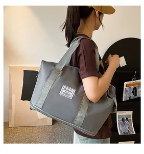 Detail view of large gray waterproof travel bag featuring dual handles and a fashion label