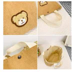 Detail view of khaki corduroy mini bag showing bear embroidery and magnetic buckle