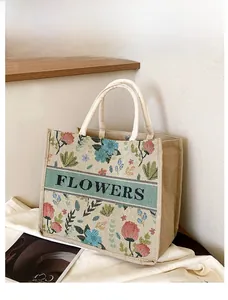 Detail showing vintage floral embroidery on beige linen tote bag with snap closure