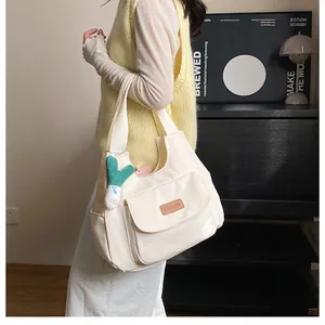 Detail of off-white canvas tote with a brown leather label and a green plush pendant