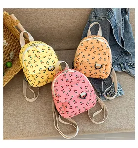 Detailed view of three corduroy mini backpacks with cherry prints in yellow, orange, and pink