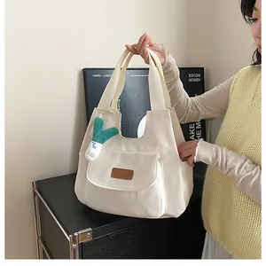 White canvas tote bag featuring brown leather patch and cute green plush pendant