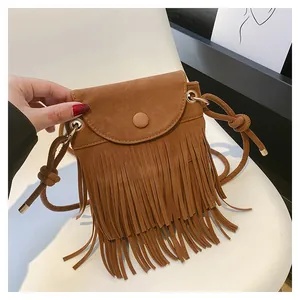 Détail du sac bandoulière en daim marron avec de longues franges et bouton doré chic
