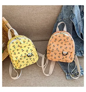Detail of yellow and orange corduroy mini backpacks with cherry patterns on a grey sofa