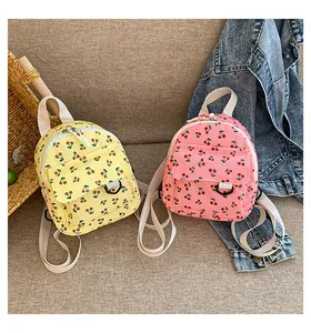 Detail view of corduroy mini backpacks with cherry prints in yellow and pink colors