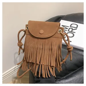 Détail du sac à franges en daim marron avec longues franges et finitions métalliques dorées