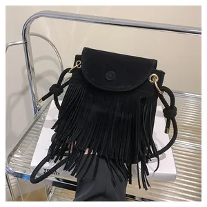 Détail du sac à bandoulière en daim noir avec franges et boucle métallique ronde