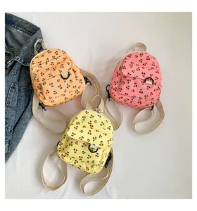 Flat lay of mini corduroy backpacks in pink, yellow, and orange with cherry patterns