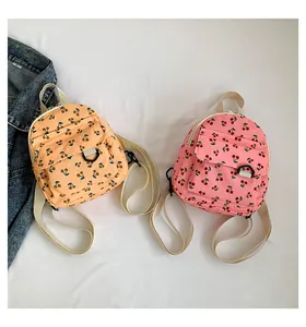 Detailed close-up of mini corduroy backpacks featuring cute embroidered cherry patterns