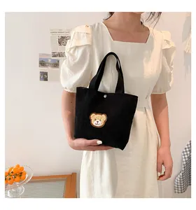 Detail of black corduroy mini tote bag with cute 3D plush bear patch and metal snap button