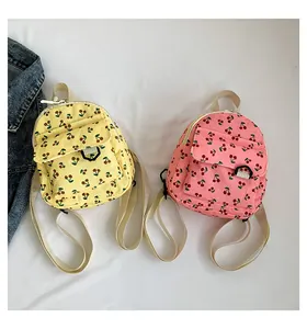 Detail of yellow and pink corduroy mini backpacks featuring cherry prints and white straps